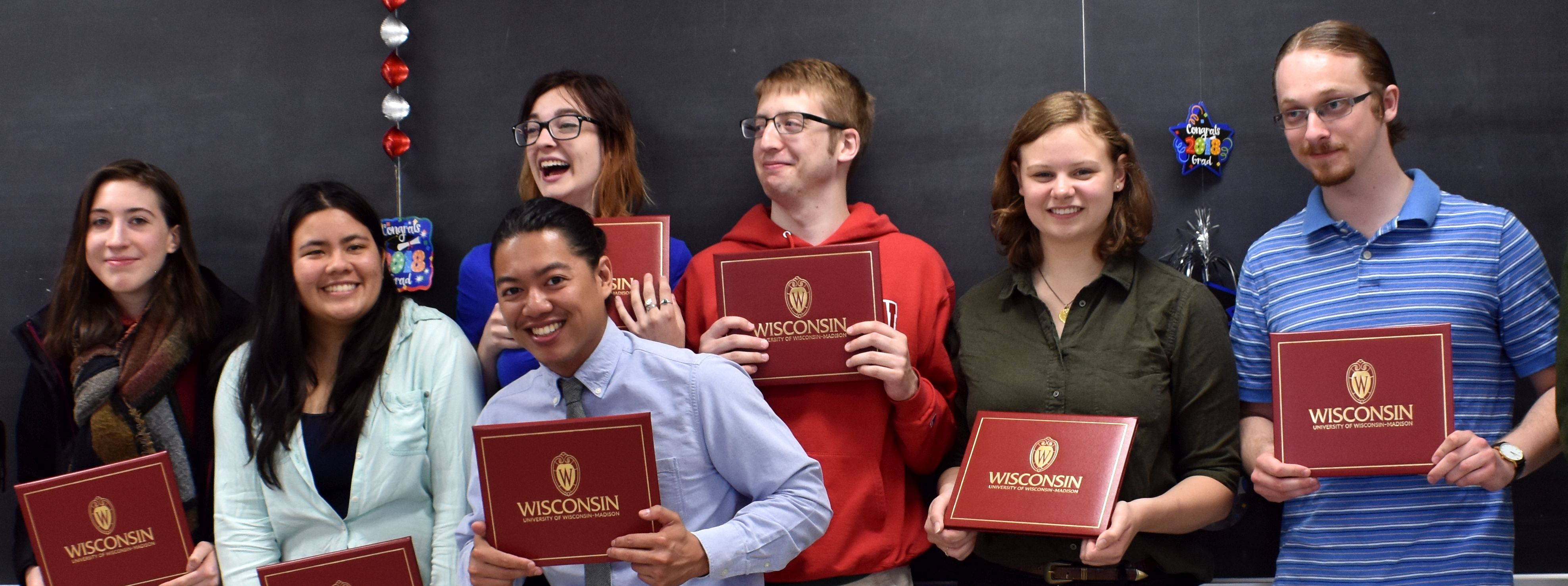 Linguistics majors holding their diplomas at a graduation celebration